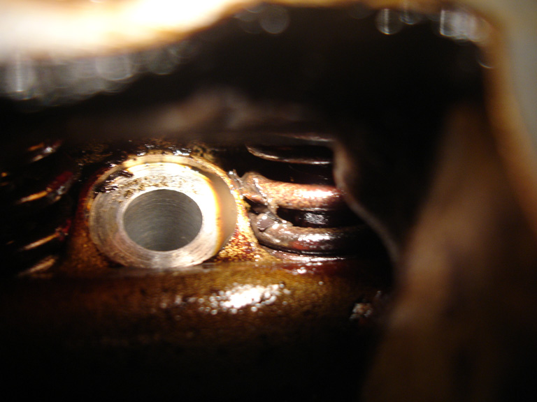 A normal valve spring, exhaust side. Except for the little fleck of sludge, this is what they are supposed to look like when you peer into the head.