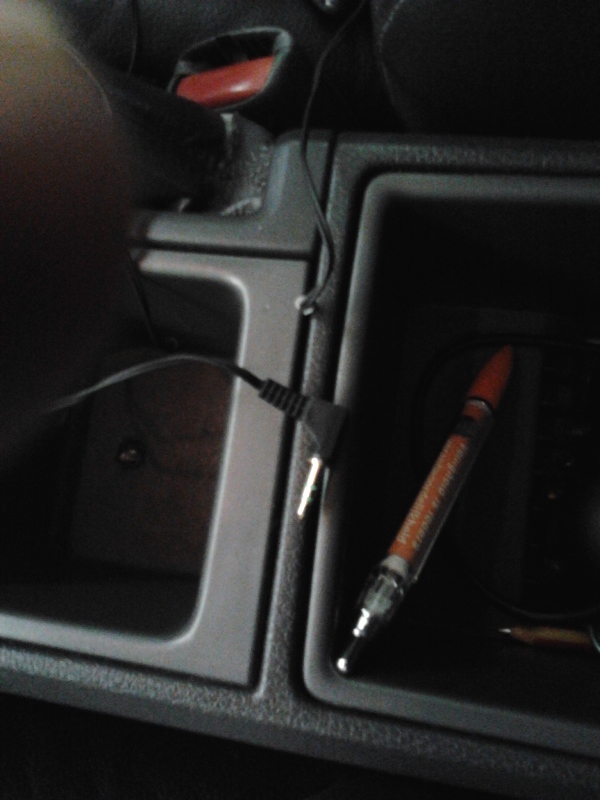 Audio wire with 3.5mm jack popping up between the back 2 console storage spaces