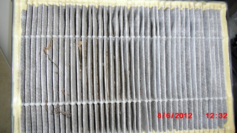 The dirty old Volvo brand cabin air filter with a solid frame. Notice the filter element is blackened by soot and intercepted plant debris.