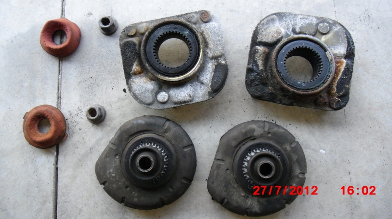 Worn OEM front strut bump stops, upper strut mount bearings, &amp; upper spring seats from a 1998 V70 XC.