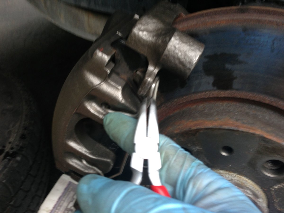 Reinstall spring - thumb pressure where index finger is, pliers pull loop down to push up on pad