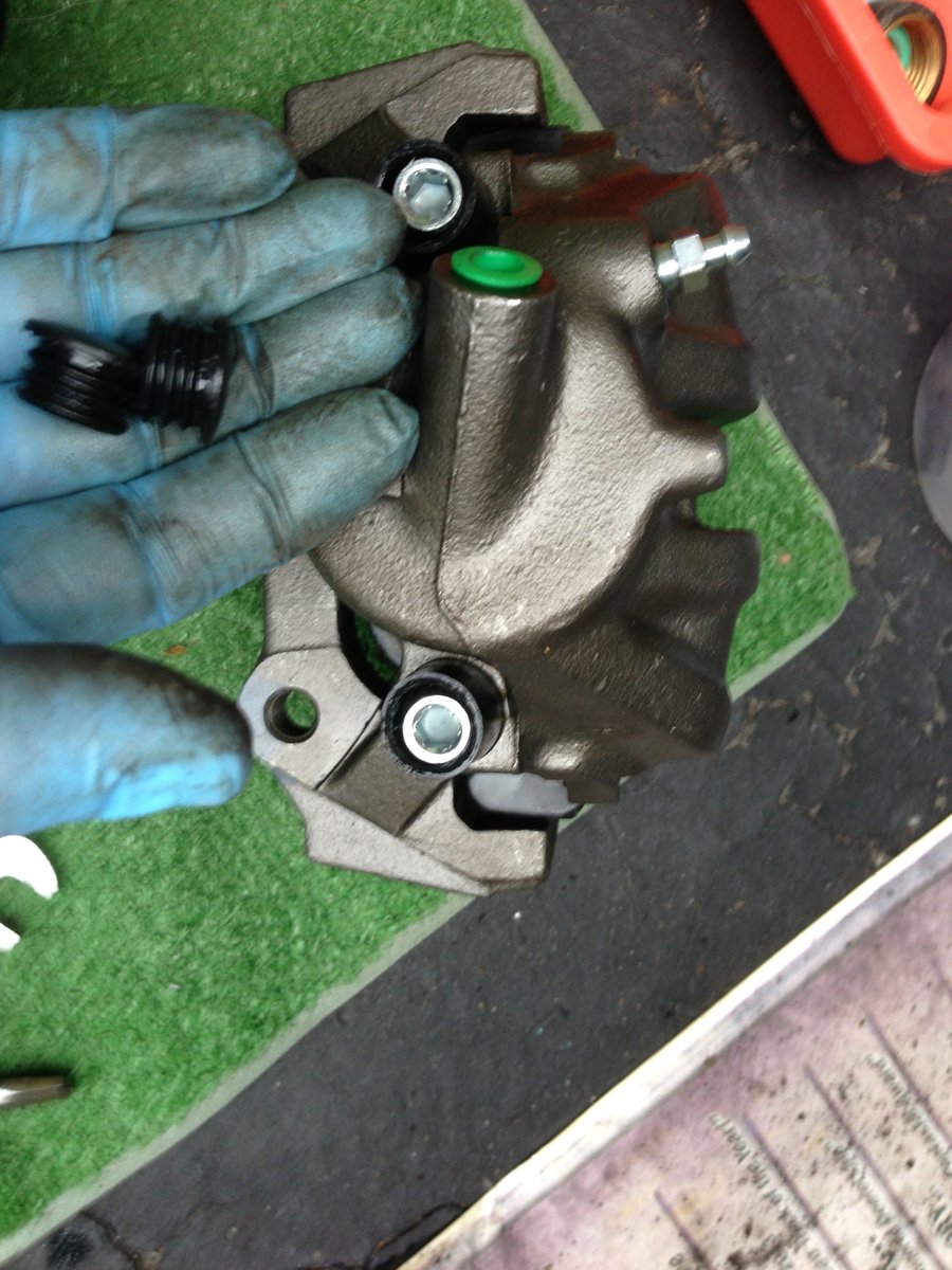 Top view of caliper in carrier - green is hose connection, silver new bleed screw, and shiny new greased caliper pins!