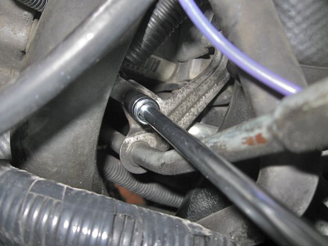 Loosening the bolt holding the clamp on the wiring harness, to free up space to get at the bolt holding the starter motor.