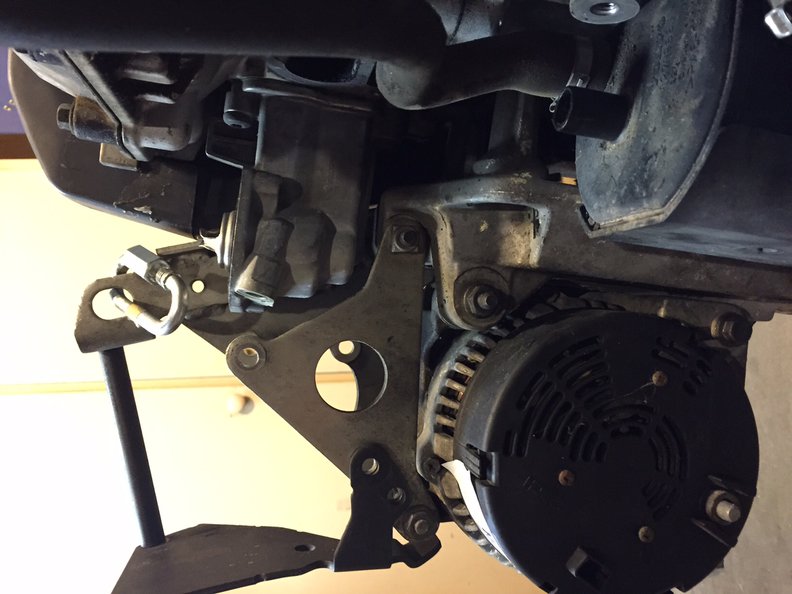 2 - Looking from the back of the alternator, not the medium size circle hole in the middle of the pic, the other two PS pump mounting holes are there. One hole at 9 o'clock has the black bracket overlaying the silver triangle bracket, the other hole at 12 o'clock is in the trainglur bracket only. The other two small PS pump mounting bolts will come in from the back through these two holes, and screw into the PS pump.