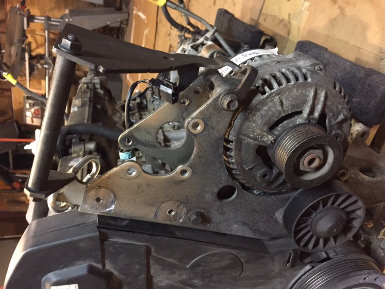 1 - Looking from the side where the serp belt is located. The long PS pump bolt/sleeve is installed across the top of the bracket but you will take it out at the end to install the PS pump. Note the 3 shiny hoes in the center, these will accept short bolts from this side to mount the PS pump at the end.