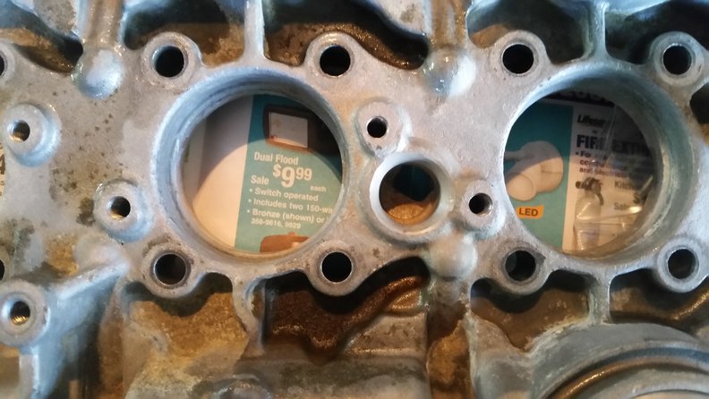 center of the picture ( micky mouse shape) between the spark plug holes.. 2 threaded holes and a passage?