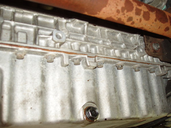 Pan prior to removal. Notice the color of the sealant. It is tarnished and hard as a rock. But what can you expect for being there for 170k miles