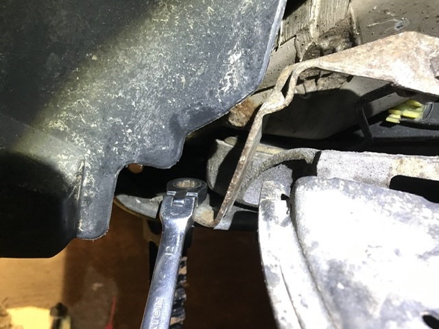 12mm bolt &amp; it slides out rearward. Undo the plastic push-clip which attaches the hard brake line to the bracket.