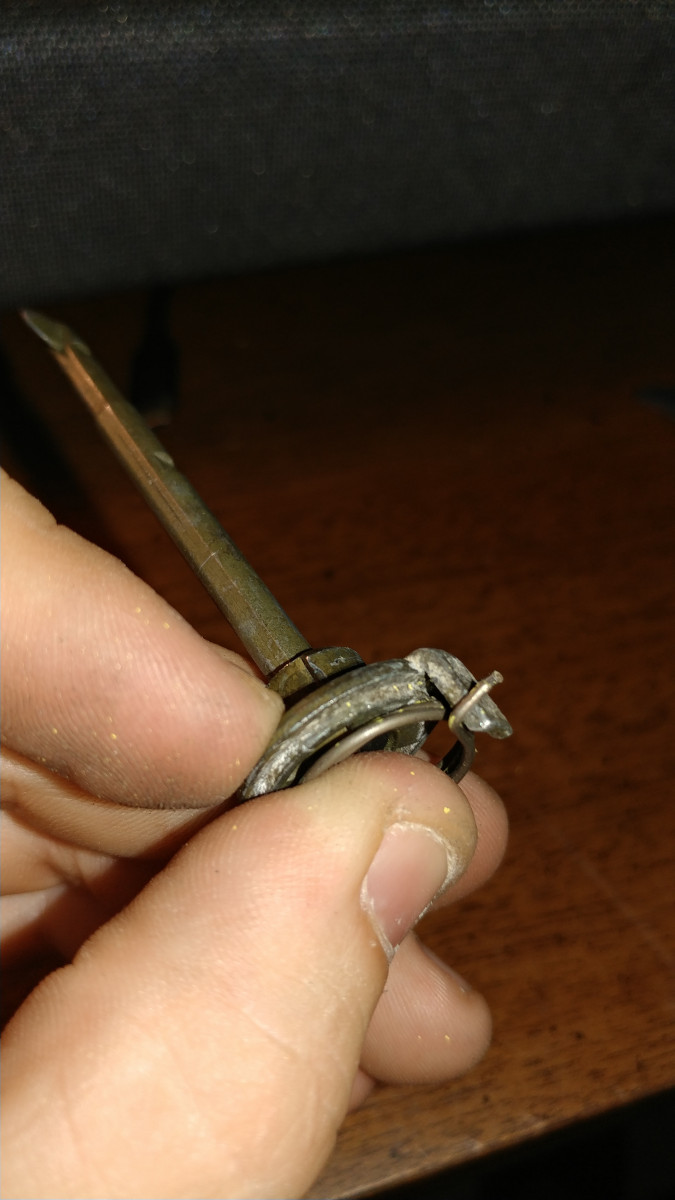 Pry up rod assembly gently with 2-3 fingers on base of rod shaft. The spring underneath will release out of place. Removal of spring is optional.