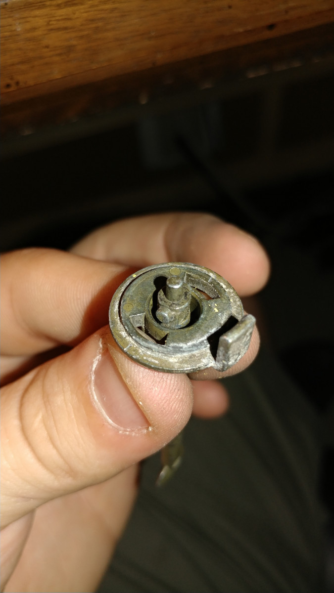 Turn removed rod assembly upside down as shown. Push the rod through the metal hook thing. You will find a black rubber piece on the end; remove that and set aside.