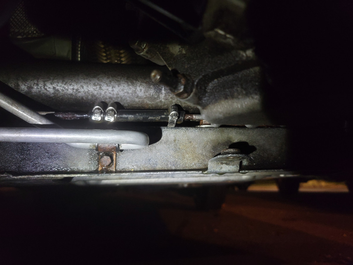 Clamped fuel line patch spanning cut and leak.