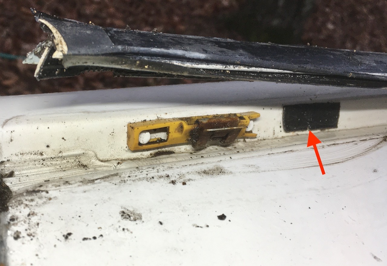 Black rubber strip covers thru-hole. Water leaks past strip and enters car here.