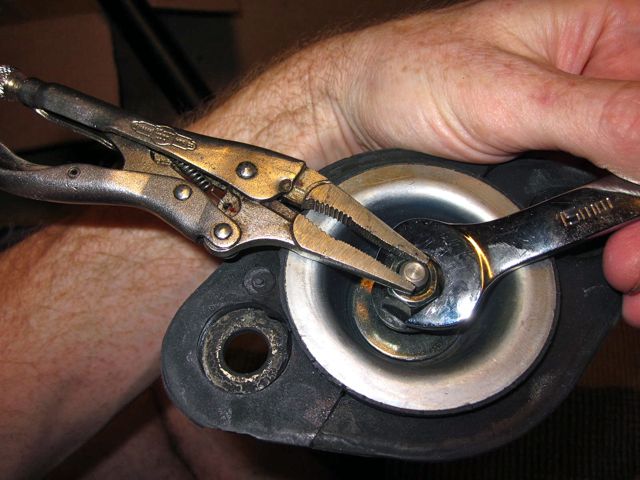 Vise grip locking pliers holding piston rod while tightening the nut