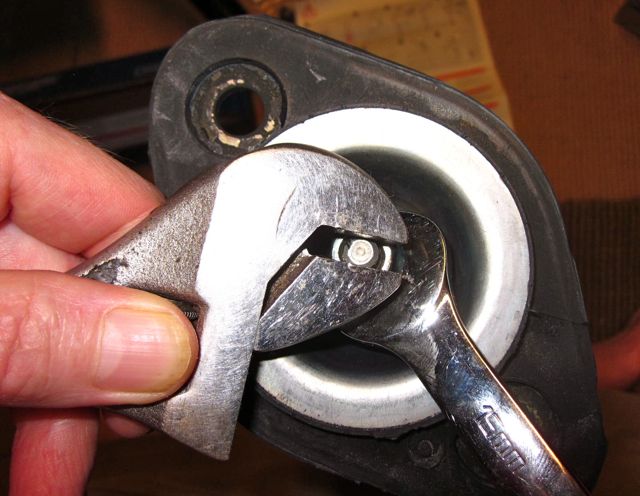 Adjustable wrench and 15mm open end wrench applying tightening torque to shock nut and piston rod