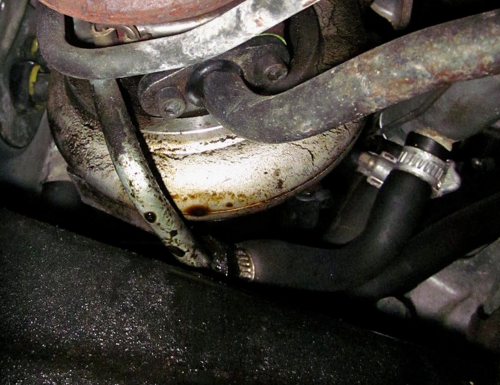 Picture of old turbo coolant inlet hose, covered in oil and starting to puff and swell.