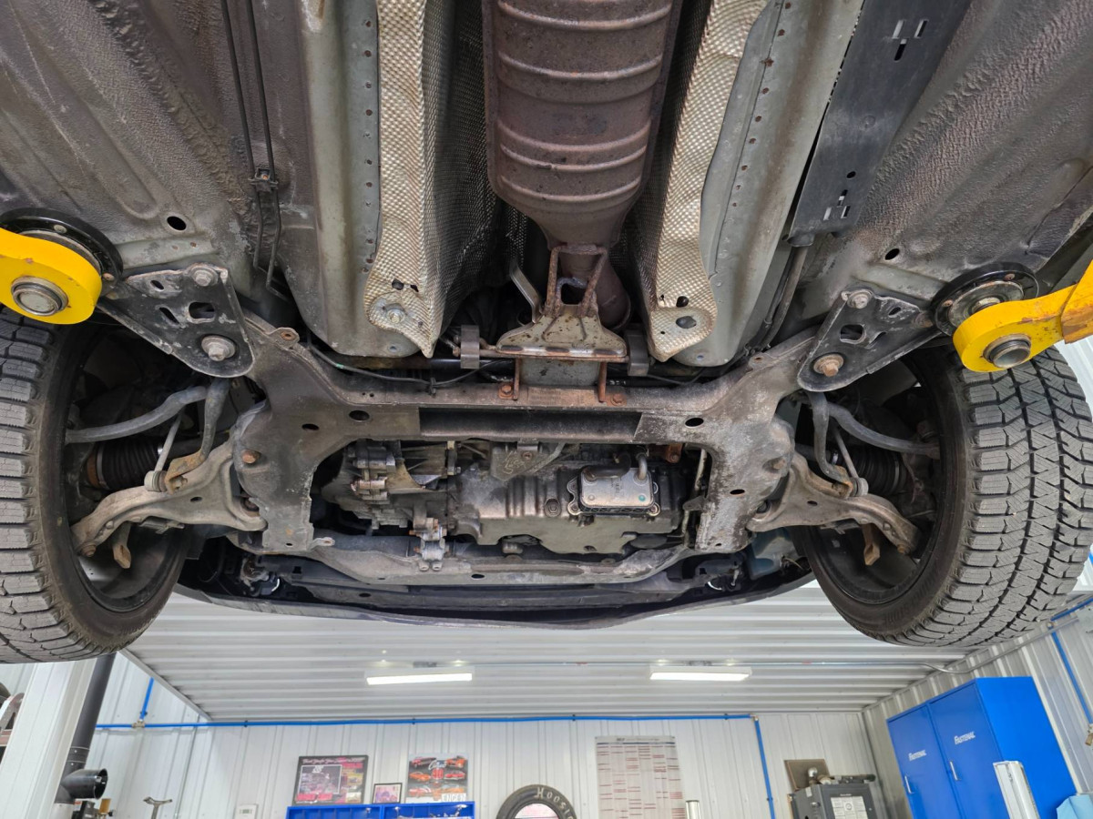 To the left of the exhaust against the heat shield you can see the black cable jacket of the rear O2 sensor. It has tension going to the engine harness connector by the turbo.